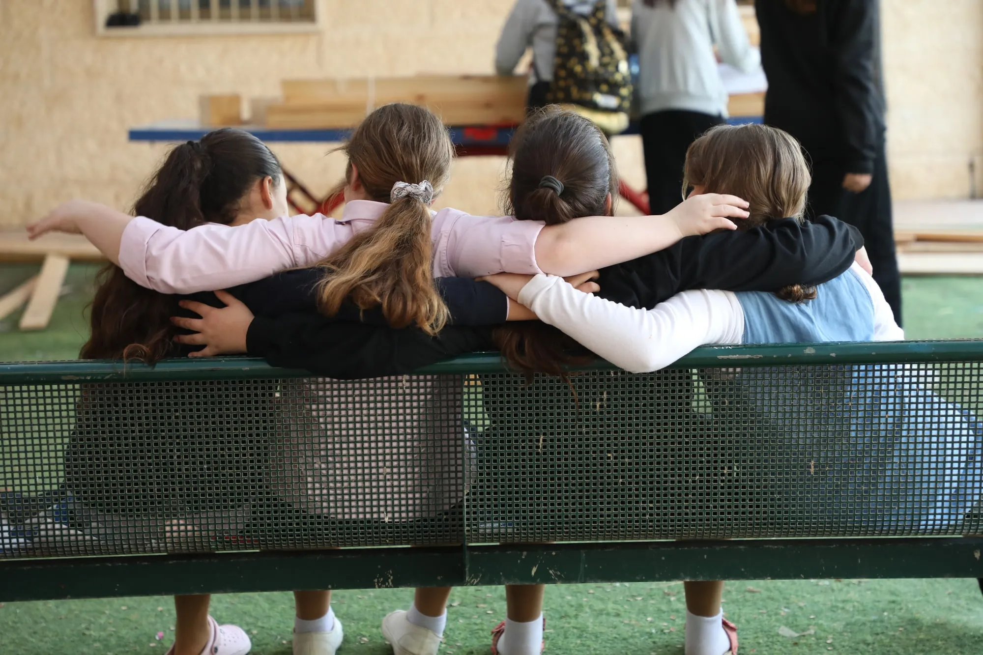 Four friends sitting arm in arm on a bench
